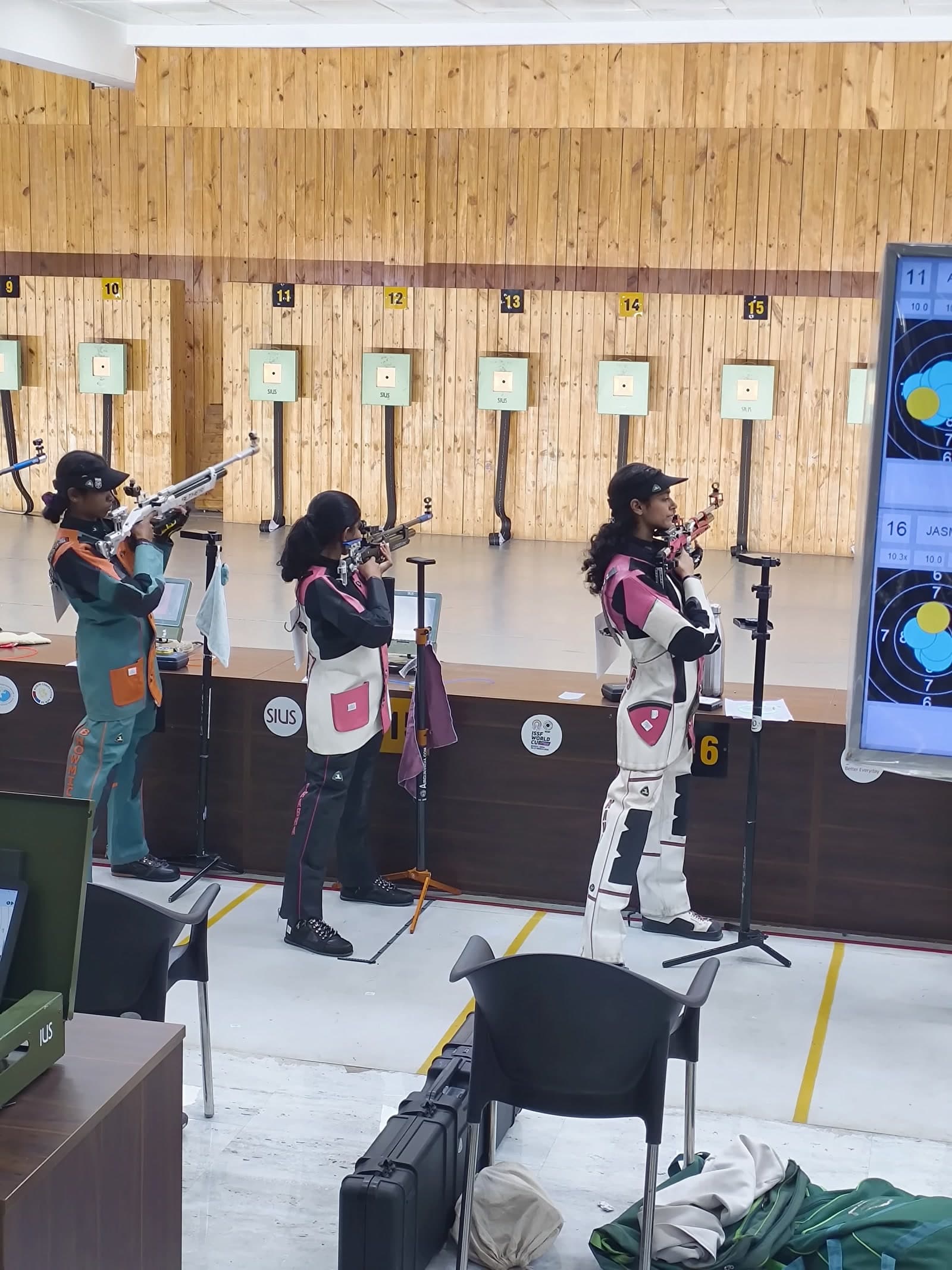 Wide view of the 10m firing line with Brahmitha G in the middle of three shooters