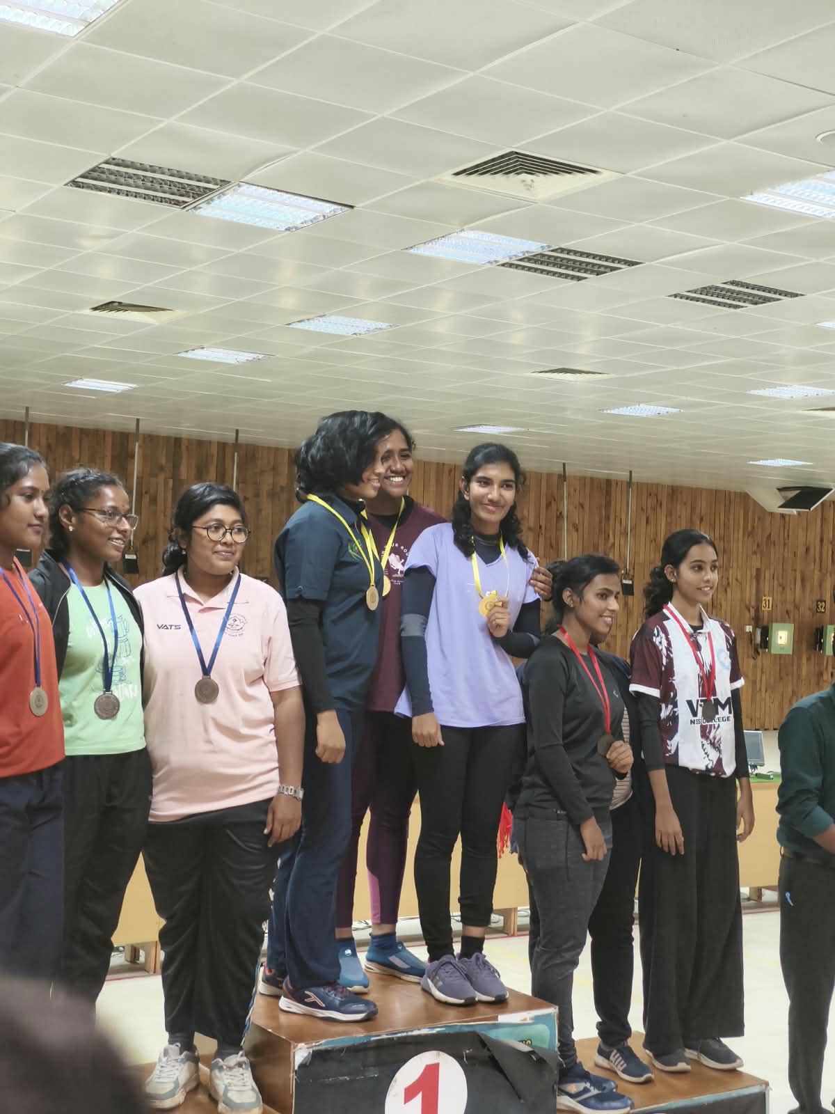 Brahmitha G on the top step of the podium with her team, holding her gold medal